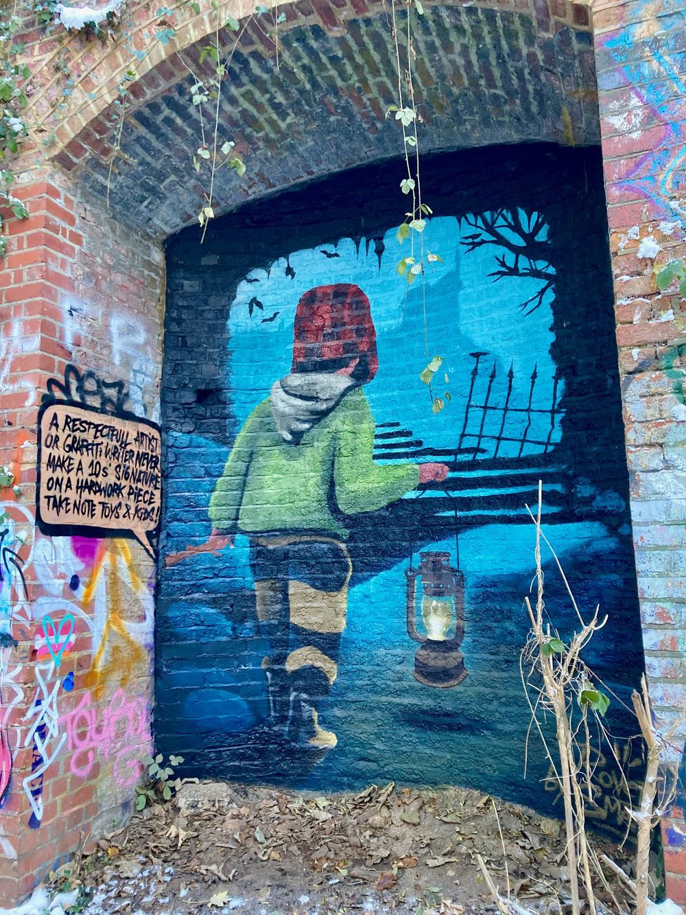 A child in a green coat holding a lantern in a blue night scene, painted on a bridge arch.
