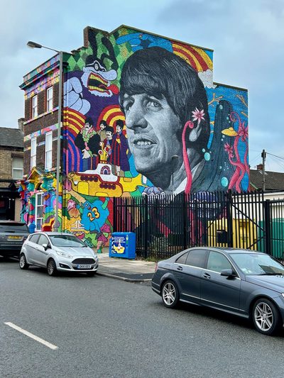 A huge black-and-white portrait of Ringo Starr, surrounded by colourful Yellow Submarine scenes with the other Beatles, painted across the end of a building.