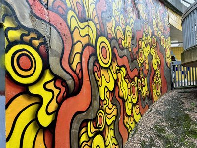Yellow, orange, red, and grey wavy shapes with concentric circles outlined in black, painted as an abstract wall mural.